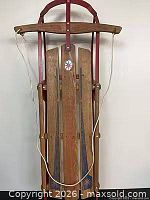 Front view of vintage wooden sled showing graphics and rope