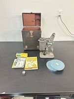 All items: Revere projector, open case, three reel tins, lamp box, manuals, lens cap