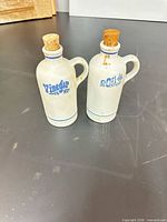 Front view of both stoneware bottles showing blue lettering and corks