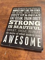 Front of black wood sign showing fitness motivational text