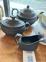 Black bisque teapot, sugar bowl, creamer, and white pitcher grouped on table