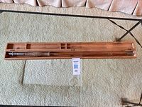 Open wooden case showing full length of rod sections and interior compartments