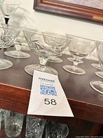 Group of etched crystal dessert coupes on shelf with MaxSold tag