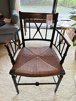 Front view of ebonized armchair showing rush seat and spindle arms