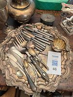 Overview of tray with flatware, pitcher, goblet, lidded jar visible