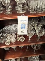 Multiple shelves of etched crystal stemware with Maxsold tag visible