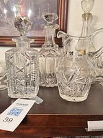 Three primary items: square cut crystal decanter, tall cut glass decanter, pinwheel crystal pitcher
