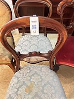 Front view of three chairs highlighting upholstery and carved frames