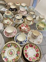 Overhead view of assorted teacup and saucer sets and stack of extra saucers