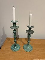 Both green metal candlesticks with candles inserted