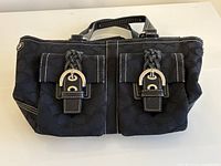Front view showing two buckle-flap pockets, fabric pattern, stitching, hardware