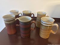 All six stoneware mugs grouped together to show quantity and varied glaze patterns