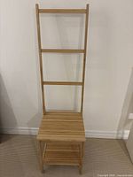 Front view of light wood ladder display stand showing three rungs, seat shelf, lower shelf