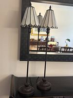 Two matching tall lamps on table showing overall design and height