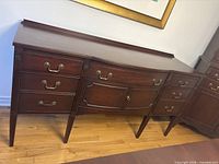 Front view showing drawers, doors, brass pulls, carved details