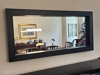 Full view of mirror mounted on wall reflecting dining area