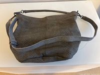 Front view of grey textured purse with strap