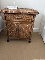 Front view of rattan nightstand showing drawer and cabinet doors