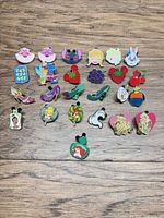 Full layout of 25 Disney enamel pins on wood surface