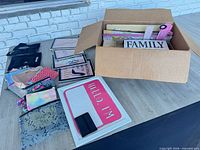 Lot overview showing box of wall art, zipper pouches, wallet