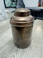 Entire coin bank showing cylindrical form and domed slot top
