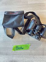 Binoculars with strap alongside Simmons-branded carry case