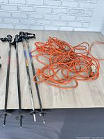 Four ski poles and orange extension cord on table
