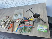 Overview of assorted tools, power strips, hammer, clamp, bungee cords and LED light fixture on table