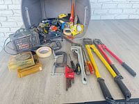 Overall view of tools including charger, bolt cutters, pipe wrench, clamps and hardware