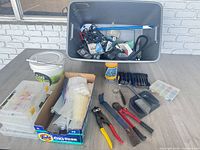 Overview of tote, tackle boxes, bucket, battery charger, spray can, assorted tools and hardware