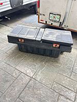Front angled view showing entire black plastic truck toolbox with both lids and copper-tone latches