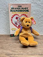 Ty Beanie Baby bear plush posed in front of handbook