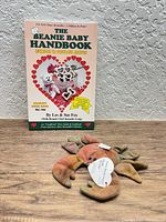 Front view of handbook standing and Claude crab plush on wood surface