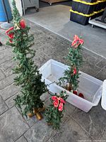 View of three artificial Christmas trees, showing size differences and wooden bases