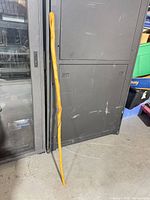 Full view of wooden walking stick leaning against cabinet