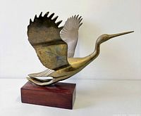 Left profile of brass stork sculpture on wood base