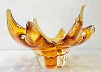 Front angled view of amber art glass bowl showing clear base and sculpted petals
