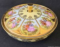 Angled view of lidded bowl showing decorative panels and gold trim