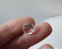 Faceted quartz gemstone held between fingers showing brilliance