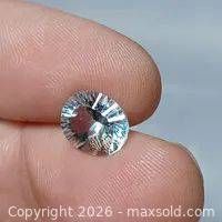 Oval blue topaz gemstone front view between fingers