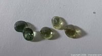 Five faceted peridot gemstones on white background