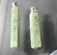 Two green hydrogrossular point pendants on dark background