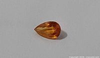 Pear-cut orange sapphire on white background