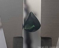 Pear-cut green tourmaline held in tweezers showing color and shape