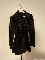 Front view of black tiger stripe Bebe jacket hanging on hanger