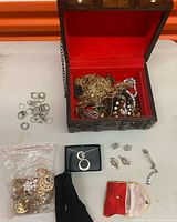 Overview of open wooden chest and loose jewelry items on table