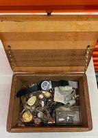 Open wooden box showing assorted jewelry and watches inside
