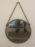 Front view of round mirror hanging, metal frame and rope visible