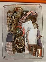 Top view of clear bin showing mixed costume jewelry pieces