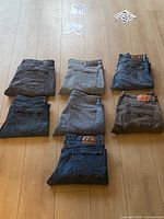 Eight folded jeans showing brand patches and wash variety